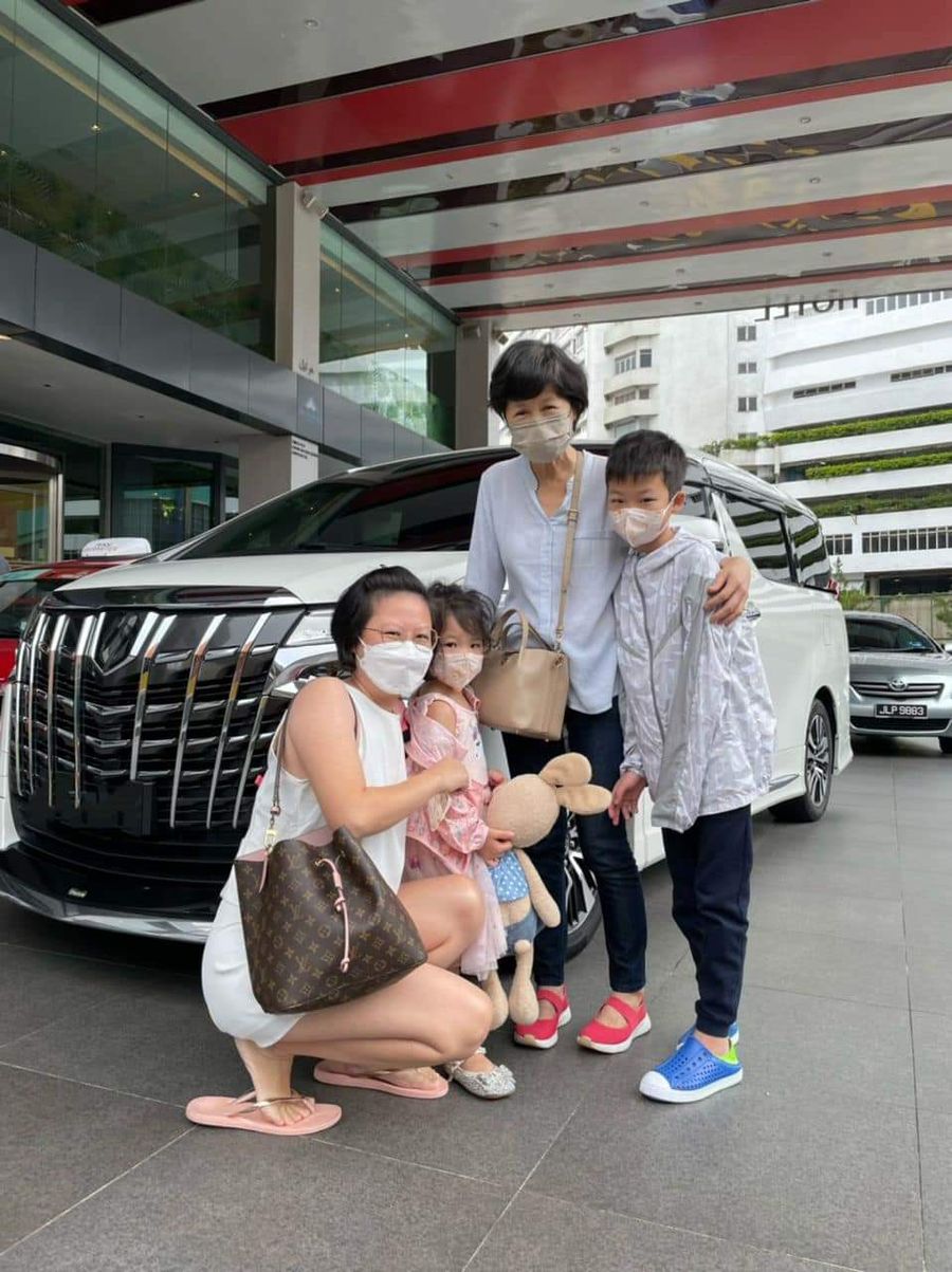 A family with two children beside a white Alphard
