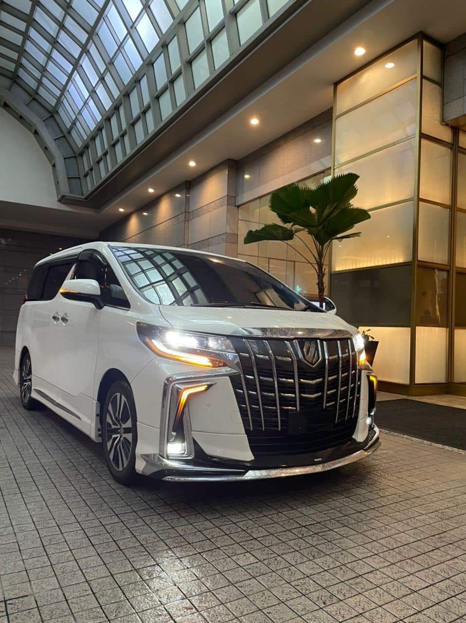 White Toyota Alphard parked under a glass canopy